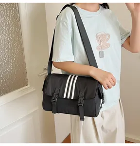 Black nylon messenger bag detailed view, casual sports style crossbody bag with three stripes.