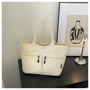 Canvas tote bag with dual front zipper pockets and comfortable handles, displayed on a clean table.