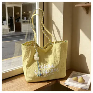 Vista dettagliata della borsa tote in tela gialla, borsa a spalla casual con ciondolo luna.