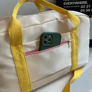 Vorderseitiges Taschendetail der weißen Sport- und Reisetasche mit gelben Griffen.