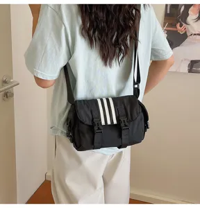 Casual black nylon crossbody bag featuring three white stripes, large capacity commuter shoulder bag.