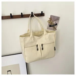 Detailed view of a minimalist canvas tote bag with front zipper pockets and comfortable handles.