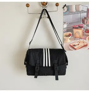 Black nylon crossbody bag with three white stripes, casual commuter shoulder bag.