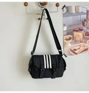 Black nylon crossbody bag detail showcasing three stripes design and dual buckle casual style.