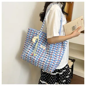 Vista dettagliata della borsa tote in tela in stile coreano con motivo ondulato e pendente.