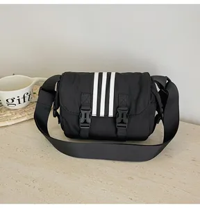 Detailed view of black nylon crossbody bag with white stripes, casual shoulder bag, adjustable strap.