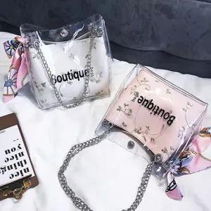 Transparent PVC jelly crossbody bag with floral embroidered inner pouch and chain strap.