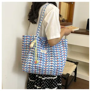 Dettaglio della borsa tote in tela in stile coreano con motivi a onde blu e graziosi ciondoli.