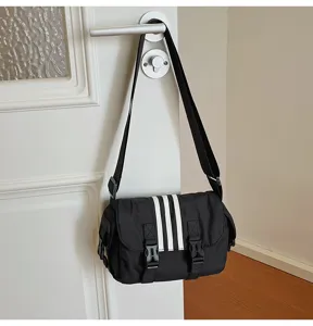 Close-up detail of the black nylon crossbody messenger bag hanging on a white door knob.