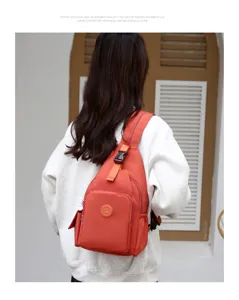 Detail view of the waterproof multi-compartment sling chest backpack in orange color.
