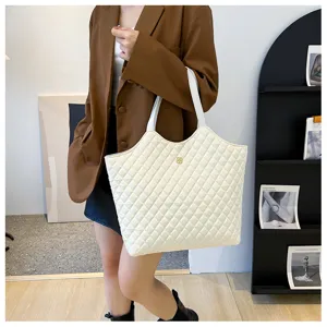 Detailed shot of white quilted tote bag showcasing fabric texture, shoulder strap and stylish design.