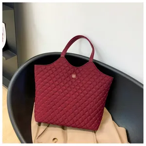 Detailed view of burgundy quilted tote bag showing texture and design on modern chair.