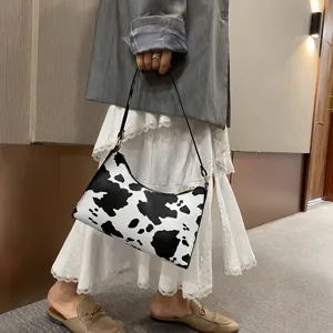 Fashionable black and white cow print underarm shoulder bag, stylish retro daily accessory.