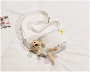 Detail view of a cute white canvas sling bag featuring a playful plush bear and zipper closure.
