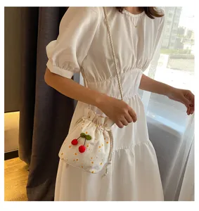 Vue détaillée d'un sac seau floral mignon avec des pendentifs cerise porté par le modèle.