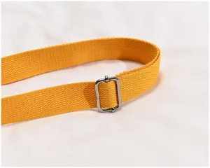 Close-up of bright yellow canvas bag strap with silver adjustable metal buckle detail.