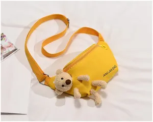 Detail view of yellow canvas crossbody chest bag with cute plush teddy bear and adjustable strap.