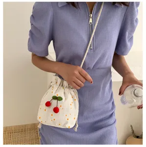 Vue détaillée du sac seau brodé de cerises mignonnes, montrant la texture et le cordon.