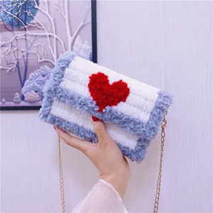 Vue detaillee du sac a bandouliere en peluche tricotee avec coeur rouge et chaine fine.