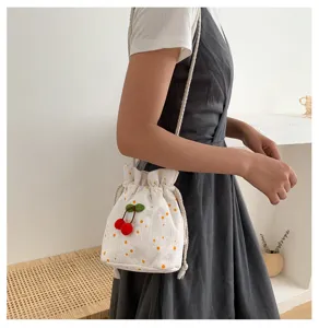 Sac seau en toile blanche avec pendentif cerise et motif marguerite pour style casual.