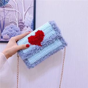 Vue détaillée du sac bandoulière en tricot pelucheux avec un cœur rouge et une chaîne.