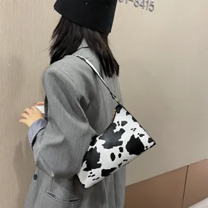 Chic black and white cow print shoulder bag for women, trendy vintage baguette purse.