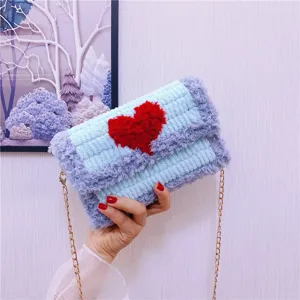 Gros plan sur le sac bandoulière tricoté duveteux fait main avec un cœur rouge et une chaîne dorée.