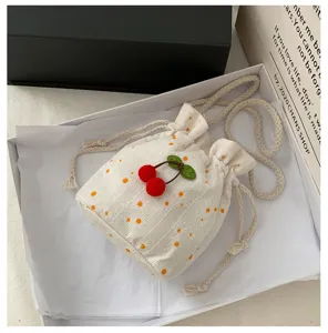 Sac seau blanc avec cordon de serrage, imprimé marguerite et décoration cerise en peluche.