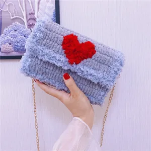 Vue détaillée du sac bandoulière duveteux avec cœur rouge et élégante chaîne dorée.