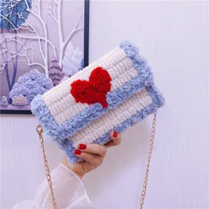 Détail en gros plan du sac bandoulière en tricot pelucheux avec motif de cœur rouge et chaîne.