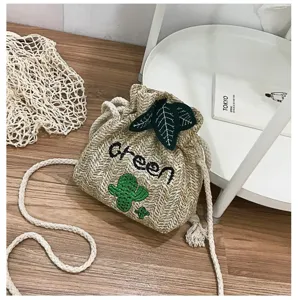 Detailed shot of cute straw bucket bag with cactus embroidery and green lettering for summer.