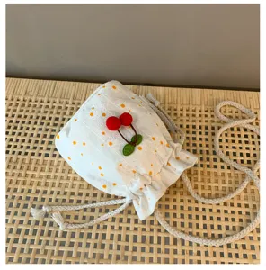 Détail du sac seau floral blanc, avec imprimé marguerite et charmant pendentif cerise rouge.