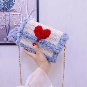 Détail de sac moelleux au crochet fait main, peluche blanche avec motif de cœur rouge.