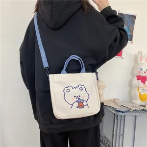 Cute canvas crossbody bag detail showing cute bear print and blue straps in daily lifestyle.