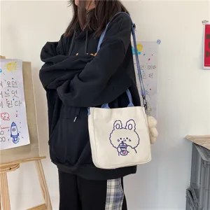 Detailed view of cute canvas shoulder bag with cartoon rabbit graphic and blue strap.