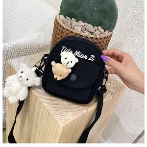Detail view of black canvas crossbody bag with cute plush bears and shoulder strap.