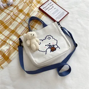 Cute canvas shoulder bag for women, featuring a sweet bear print and plush pendant detail.