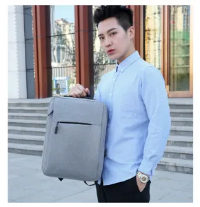 Dettaglio di uno zaino da lavoro grigio minimalista tenuto da un modello con stile casual.