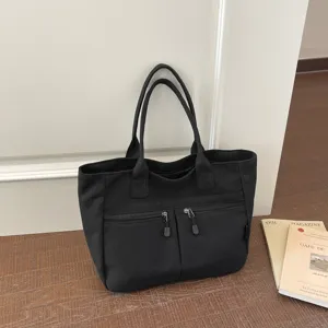 Black canvas tote bag with dual handles and front zipper pockets, simple casual style for daily use.