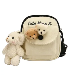 Cute canvas crossbody bag for women with plush bear charms, casual shoulder phone bag.