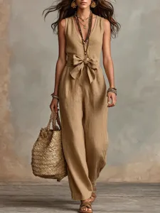 Gros plan sur les détails du combi-pantalon en lin pour femme, col en V et ceinture à nœud.