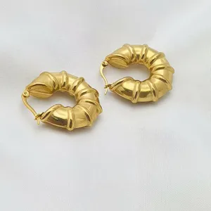 Detailaufnahme von goldenen edelstahl ohrringen im vintage stil mit markanter struktur.