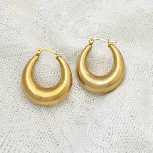 Goldfarbene edelstahl dicke creolen detailansicht mit glatter polierter oberflaeche.