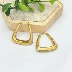 Detailaufnahme von goldenen geometrischen Edelstahl-Creolen mit glänzender Metallstruktur.