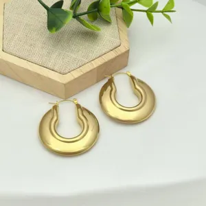 Detailaufnahme von dicken goldenen U-förmigen Creolen mit glänzender Metalloberfläche.