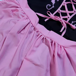 Détail de robe de servante bavaroise Oktoberfest avec jupe plissée rose et haut corset noir.