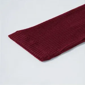 Burgundy knitted ribbed fabric detail, showing soft texture and fine cuff craftsmanship.