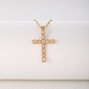 Gold cross pendant necklace featuring sparkling cubic zirconia stones in an elegant design detail.