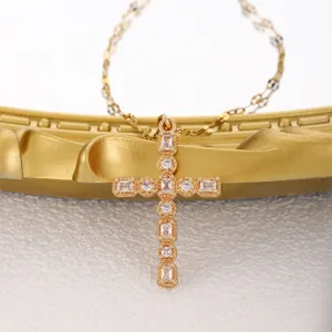 Gold cross pendant necklace featuring shimmering round and baguette cubic zirconia. Elegant.