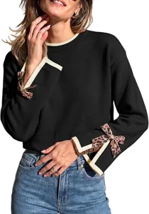 Detailed view of women's knit sweater with contrast cuffs and leopard bow design closeup.